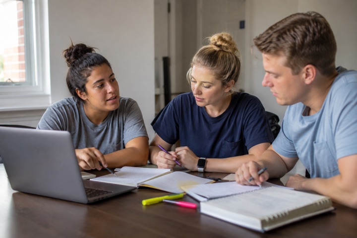 A study group of EMS students reviewing material together with a laptop and notes